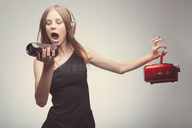 Joyable attractive fashion pretty girl listening music with headphones, speaker, record player, holding them in hands and wearing