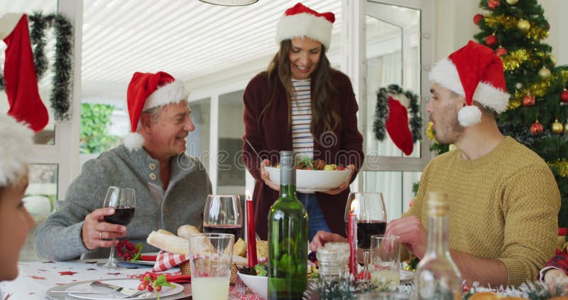 Joyeuse famille caucasienne multi génération portant des chapeaux santa avec repas de noël banque de vidéos