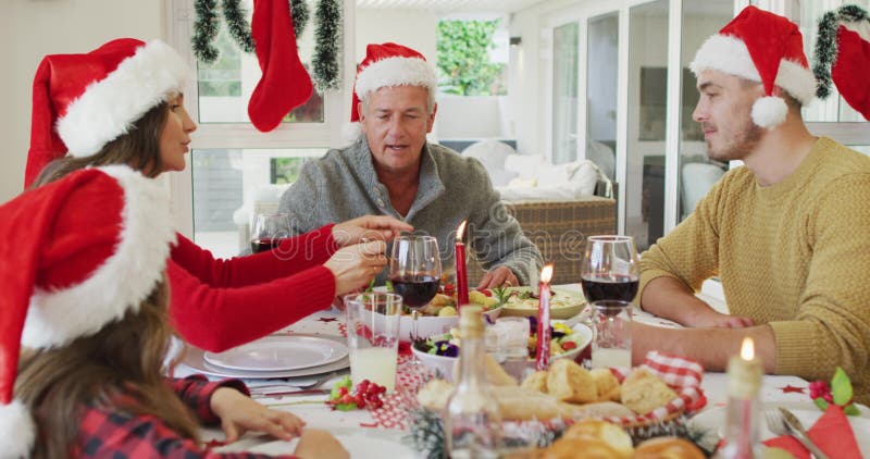 Joyeuse famille caucasienne multi génération portant des chapeaux santa avec repas de noël clips vidéos