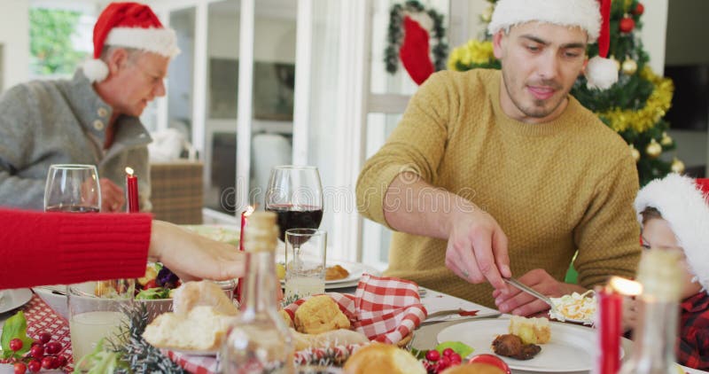 Joyeuse famille caucasienne multi génération portant des chapeaux santa avec repas de noël banque de vidéos