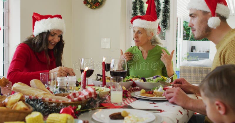 Joyeuse famille caucasienne multi génération portant des chapeaux santa avec repas de noël banque de vidéos