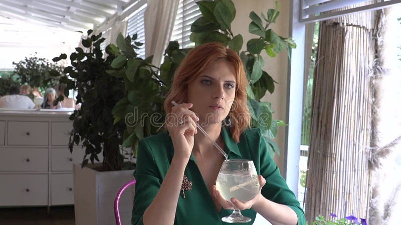 Joyeuse femme caucasienne buvant un cocktail de paille dans un café de rue. Mouvement lent. banque de vidéos