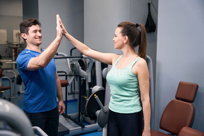 Joyeuse femme saluant son instructeur de fitness avant l'entraînement photos stock