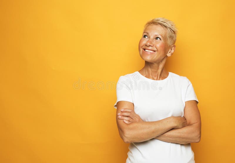 Joyeuse femme âgée souriante avec bras croisés gros portrait sur fond jaune. photos libres de droits