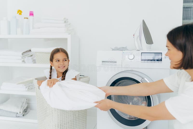 un enfant occupé fait la lessive, vide la machine à laver, nettoie