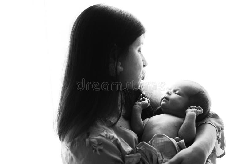 Joyeuse fête des mères! Élégante Mère tenant et embrassant mignon nouveau-né bébé dans la fenêtre lumière proche. Maternité et parentalité. Adoption et concept de fertilité