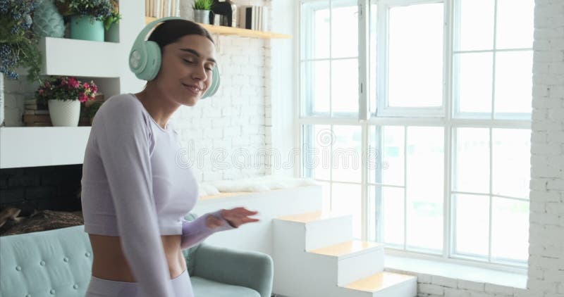 Joyeuse jeune femme dansant seule à la maison et utilisant un smartphone pour écouter de la musique banque de vidéos