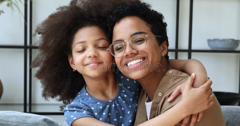 Joyeuse jeune fille africaine fille câlin maman bien-aimée avec les yeux fermés