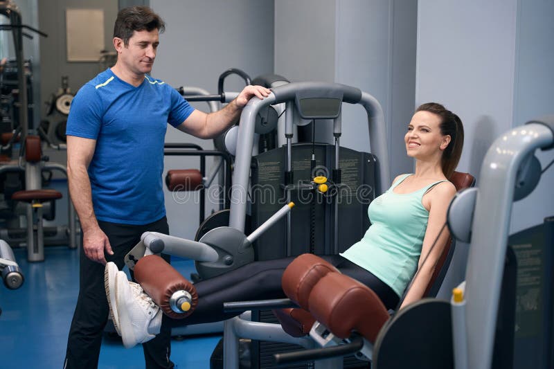 Joyeuse mature femelle faisant de l'entraînement en bas du corps supervisé par l'instructeur de fitness images stock