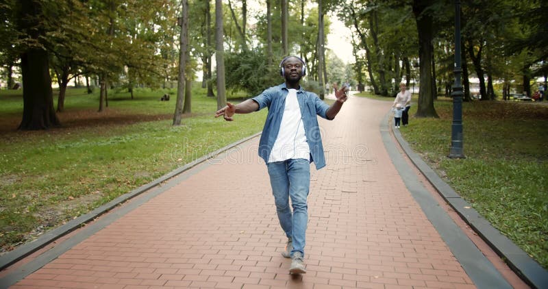Joyeuses danses afro-américaines sur des écouteurs dans un parc banque de vidéos
