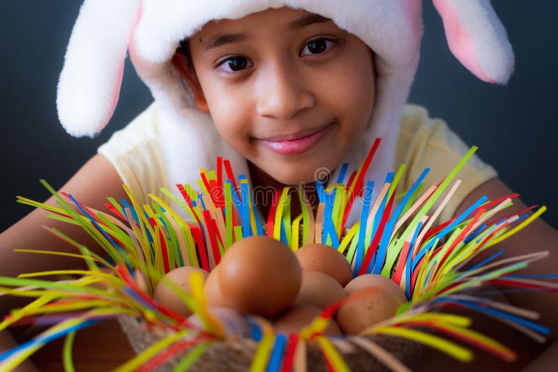 Joyeuses P?ques ! Fin vers le haut de chapeau de port de lapin de fille mignonne avec des oeufs de poulet dans un panier image libre de droits Joyeuses P?ques ! Fin vers le haut de chapeau de port de lapin de fille mignonne avec des oeufs de poulet dans un panier image libre de droits