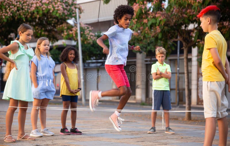 Groupe D'enfants Enjoués Sauter Ensemble Avec La Corde À Sauter Sur Terrain  De Jeu Urbain Banque D'Images et Photos Libres De Droits. Image 64998473