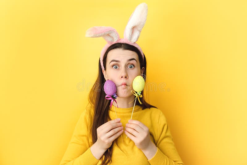 Joyeux et drôle beau sourire jeune femme 20 ans portant des oreilles de lapin tenant des oeufs de pâques colorés joueuse brune fem image stock