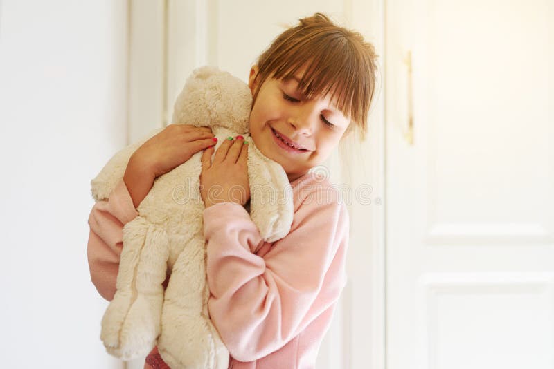Joyeux fille embrasser et l'amour avec l'ours en peluche pour le confort doux jouet ou poupée ludique à la maison. petit enfant ou image stock
