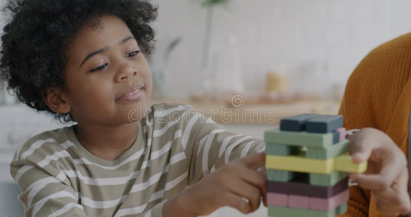 Joyeux garçon afro-américain jouant avec un jouet en bois cool jouant avec un parent à la maison clips vidéos