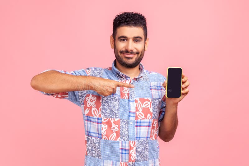 Joyeux homme perlé en bleu casual chemise pointant du doigt sur le smartphone avec écran vide regardant l'appareil photo avec sour image libre de droits