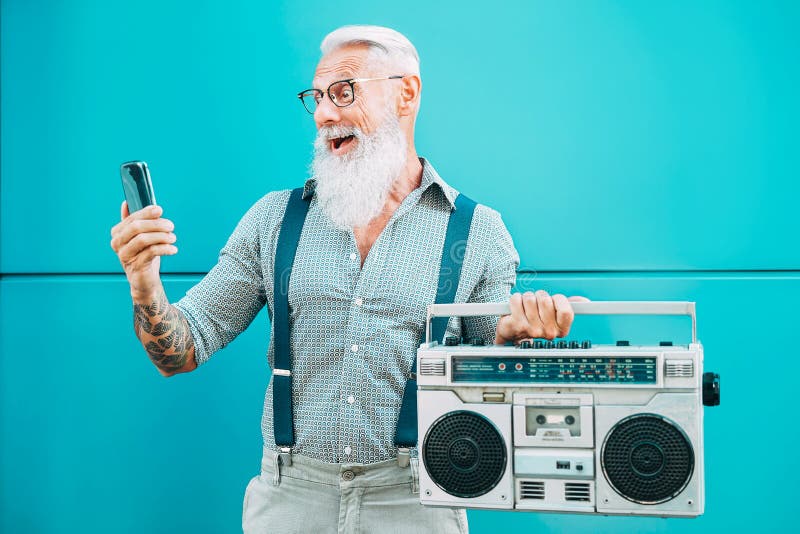 Joyeux homme âgé utilisant un téléphone portable tout en tenant une boombox vintage à l'extérieur - Homme branché de mode jouant photos libres de droits Joyeux homme âgé utilisant un téléphone portable tout en tenant une boombox vintage à l'extérieur - Homme branché de mode jouant photos libres de droits