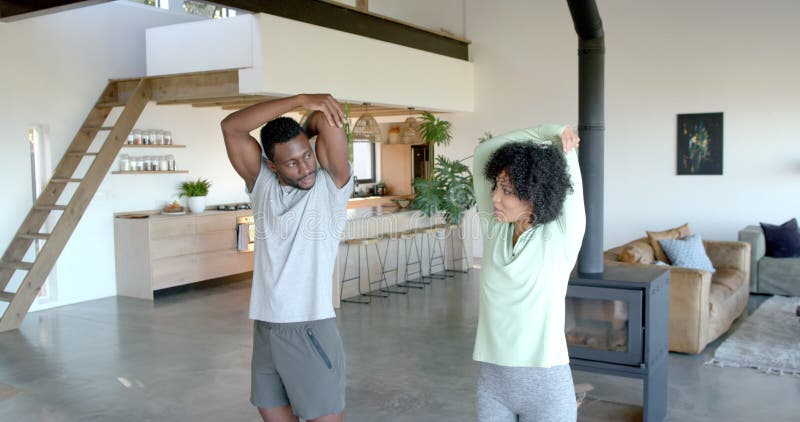 Joyeux jeune couple faisant du yoga s'étirant ensemble dans le salon moderne banque de vidéos