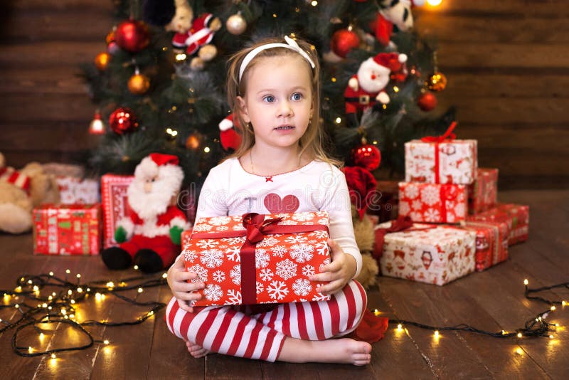 Joyeux Noël et joies fêtes Nouvel An 2020 Concept de vacances de Noël Petite fille mignonne en pyjama rayé rouge assise en C photo stock Joyeux Noël et joies fêtes Nouvel An 2020 Concept de vacances de Noël Petite fille mignonne en pyjama rayé rouge assise en C photo stock