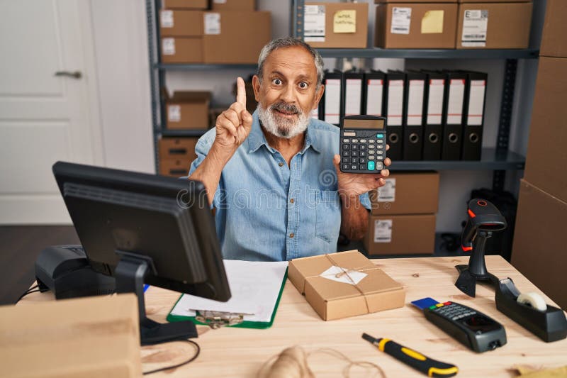 Joyeux senior man doigts pointant avec une idée tenant une calculatrice au bureau. le visage souriant éclaire la pièce l'esprit confiant excité plein de questions. numéro un en comptabilité