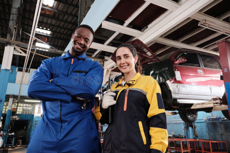 Joyeux travail d'équipe mécanique sourire joyeux dans un garage de voiture fixe. image stock