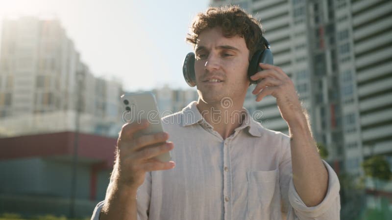 Joyeux étudiant européen caucasien en train d'écouter de la musique écouteurs écouteurs danser avec un smartphone portable banque de vidéos