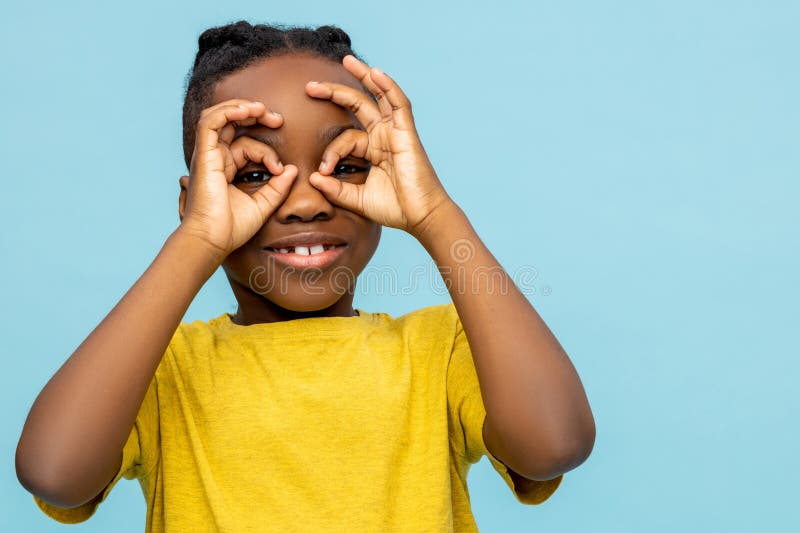 Joyful African American little boy making binoculars with hands stock image