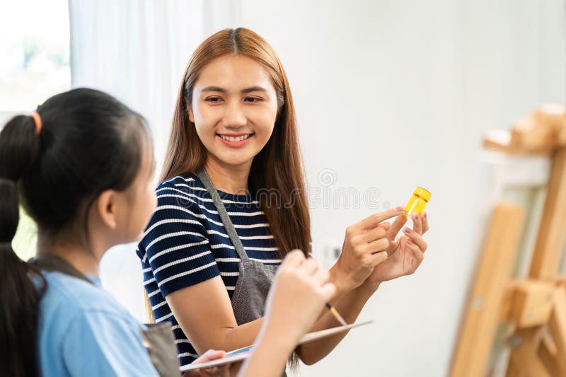 Joyful Art Lesson: Woman and Girl Discussing Paint Colors stock image