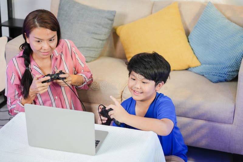 Joyful Asian Child Spela videospel med förälder mamma och son Enjoeing Online Gaming Tillsammans med mor och son Bonding over Vide royaltyfri fotografi
