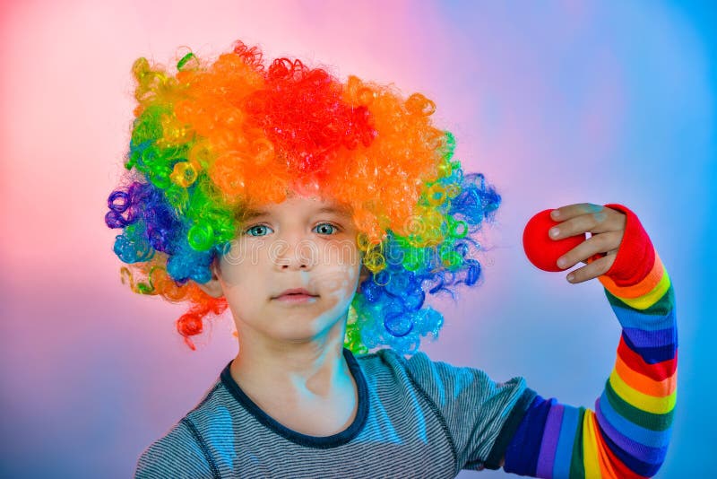 Joyful Boy in a Clown Wig Holds a Red False Nose in His Hand Stock