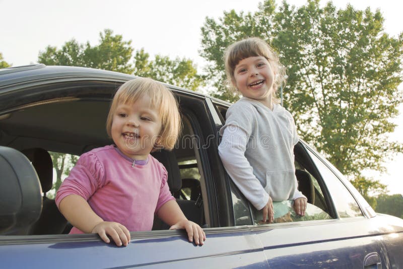 Joyful children look out of the car