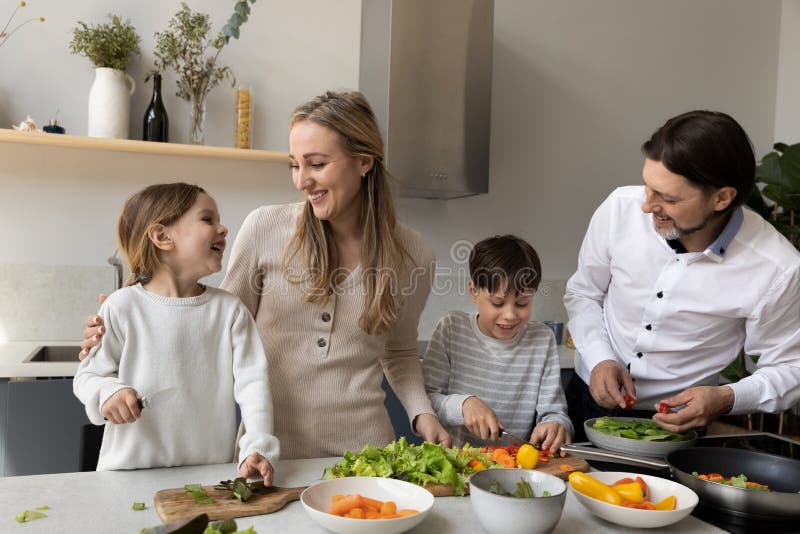 Joyful cute sibling kids helping parents to prepare dinner