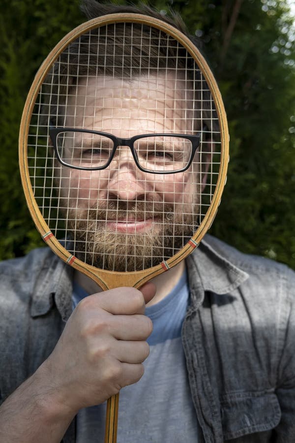 A joyful, funny man put glasses on a badminton racket and leaned against his face for a joke royalty free stock photos A joyful, funny man put glasses on a badminton racket and leaned against his face for a joke royalty free stock photos