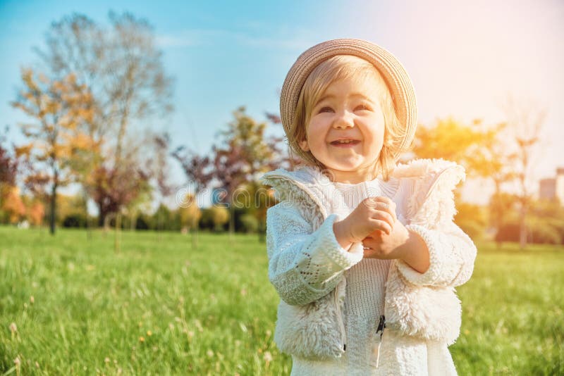 Joyful little caucasian child girl walks in the park and claps her hands