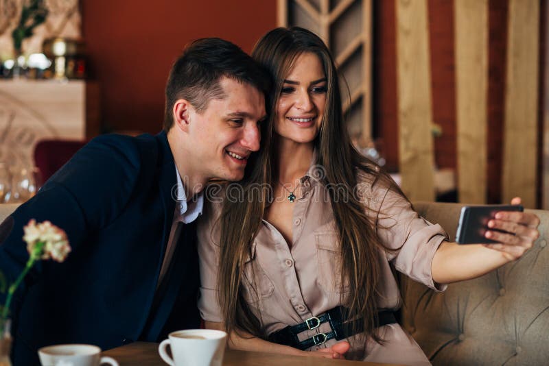 Joyful loving couple enjoying modern technology, having fun, capturing bright moments of vacations in cafe royalty free stock photo Joyful loving couple enjoying modern technology, having fun, capturing bright moments of vacations in cafe royalty free stock photo