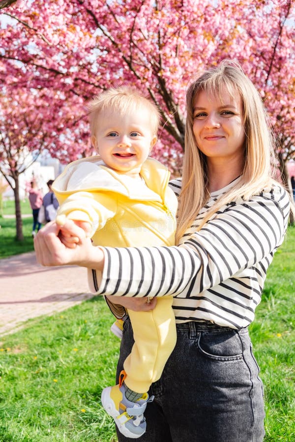 Mama și copilul vesel, sub arbore sakura înfloritor. stock images