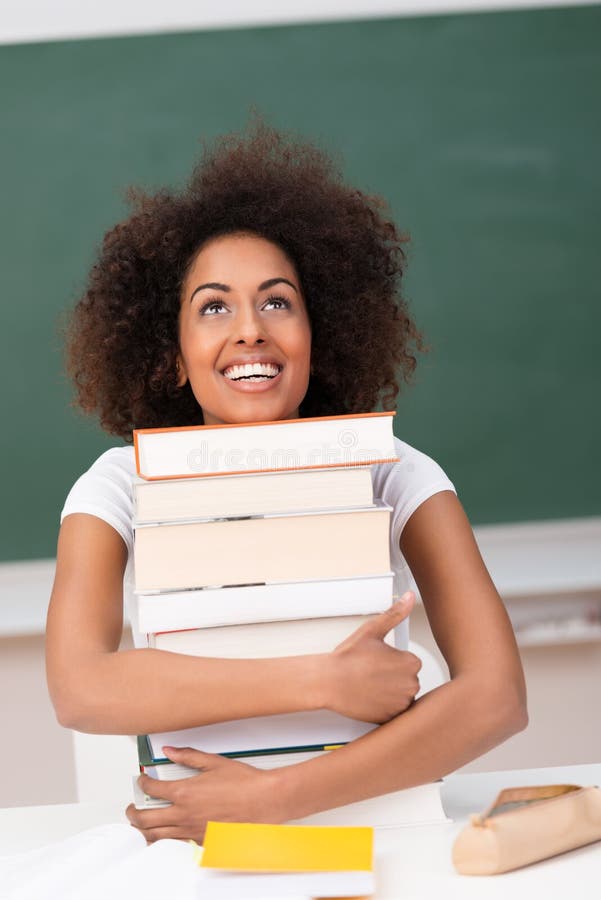 Joyful student hugging her text books stock image