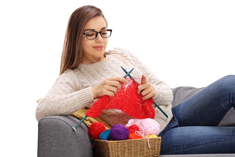 Joyful woman lying on a sofa and knitting