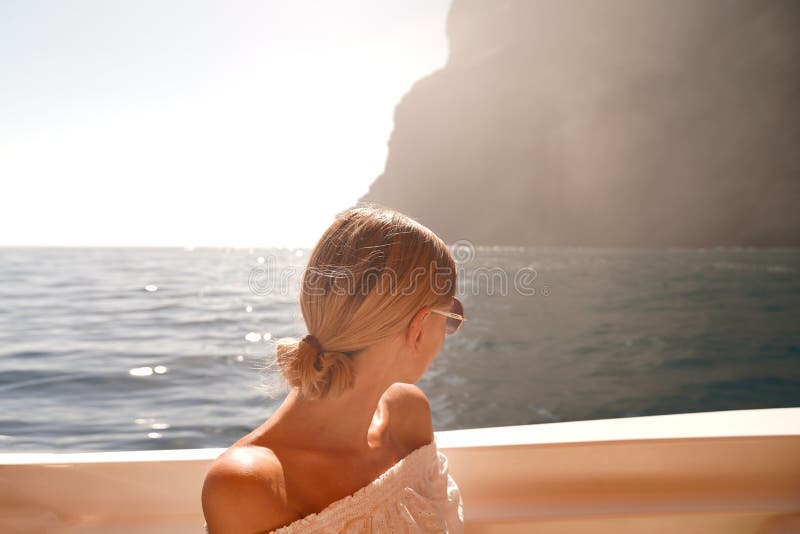 Joyful woman on sailing boat discovering island coast on summer cruise