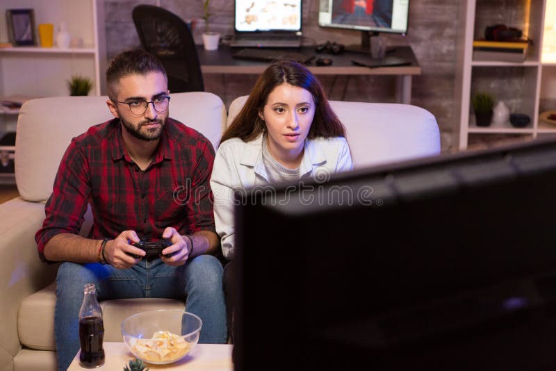 Couple Playing Video Games on Big Screen TV in the Living Room Late at