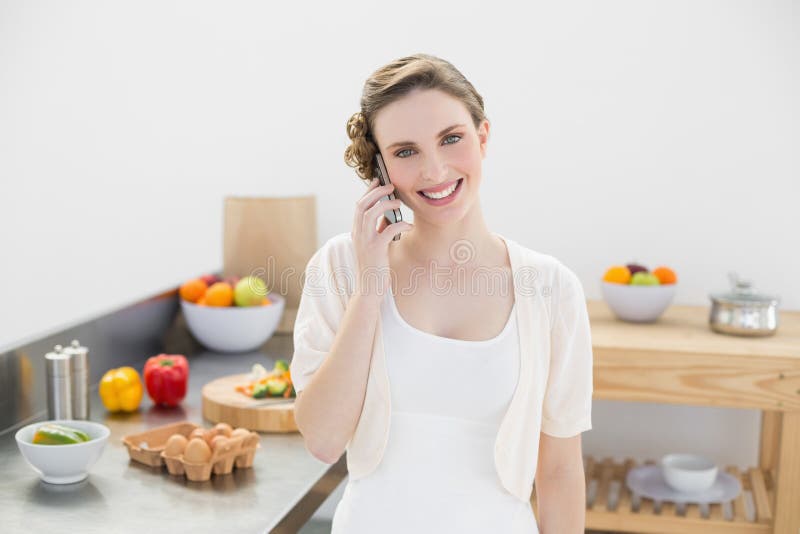 Joyful young woman phoning with her smartphone standing in kitchen royalty free stock photography Joyful young woman phoning with her smartphone standing in kitchen royalty free stock photography