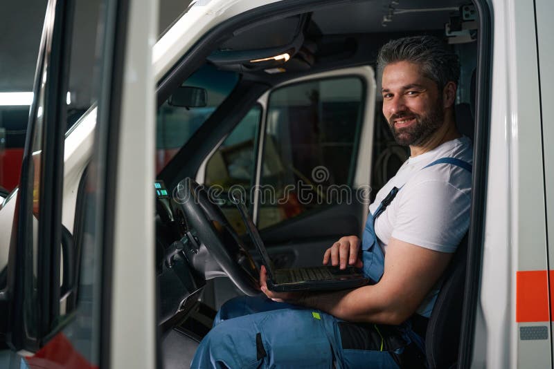 Joyous automotive mechanic conducting computer diagnostics on motor vehicle