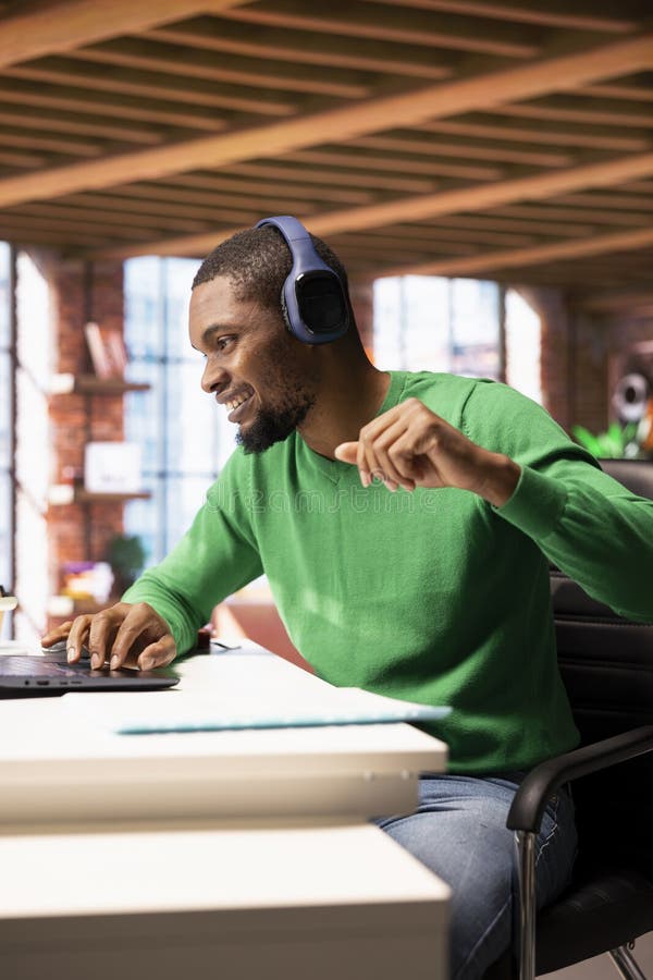 Joyous man wearing headphones watching TV show on laptop stock photo