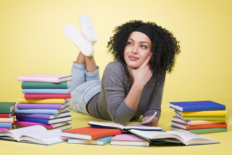 Joyous student girl reading surrounded by colorful books.