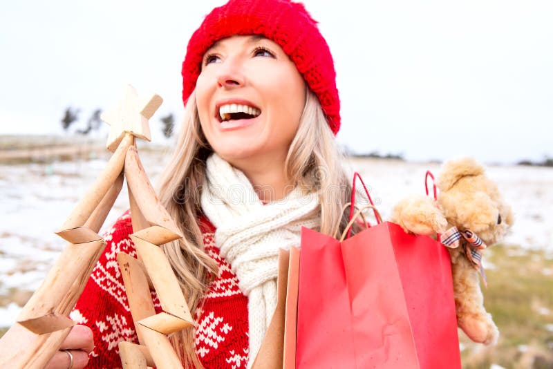 Joyous woman holding small wooden Christmas tree and gift bags. Joyous womwn holding timber Christmas tree and gift bags in a snowy landscape. Blue Mountains stock photos Joyous woman holding small wooden Christmas tree and gift bags. Joyous womwn holding timber Christmas tree and gift bags in a snowy landscape. Blue Mountains stock photos