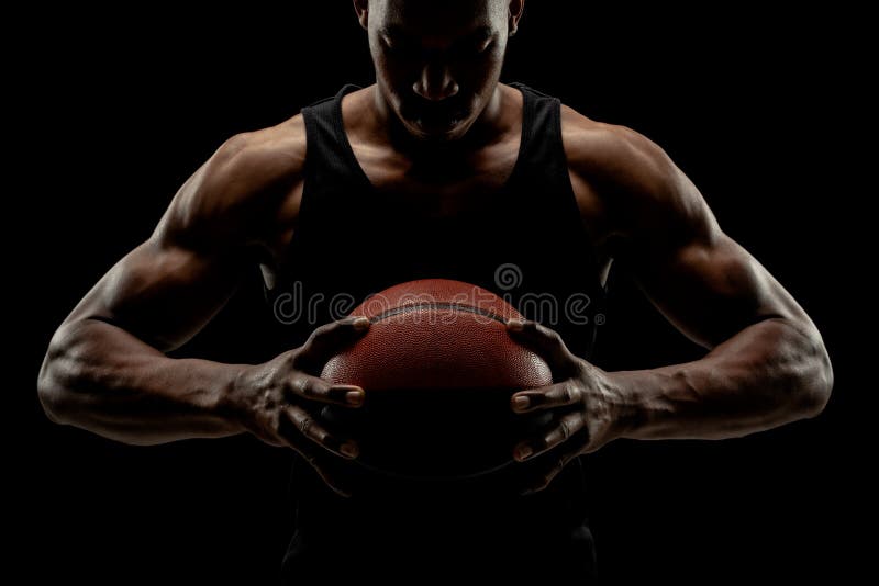 Jucător de baschet care deține o minge pe fond negru. american concentrat serios stock photos