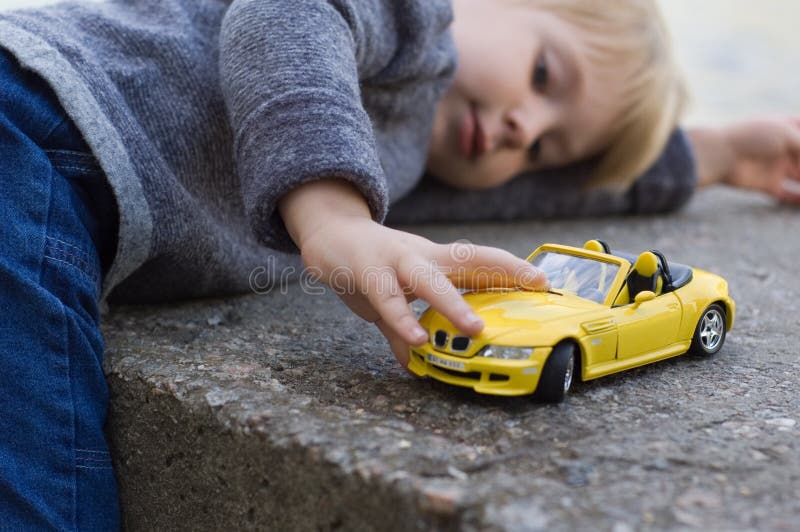 Juego del niño pequeño con un coche imágenes de archivo libres de regalías Juego del niño pequeño con un coche imágenes de archivo libres de regalías