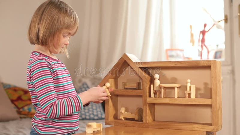 Juego independiente en kindergarten chica juega con una casa de madera centrada en el juego