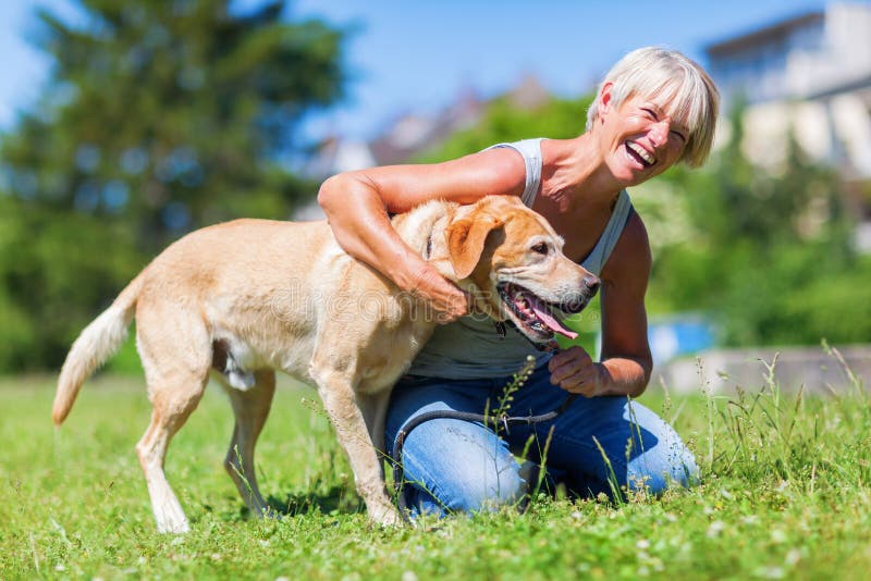 Juegos maduros felices de la mujer con un perro fotografía de archivo Juegos maduros felices de la mujer con un perro fotografía de archivo