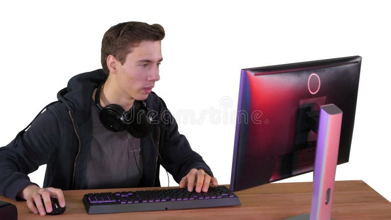 Jugador chico con auriculares jugando videojuegos en el ordenador y mostrando el pulgar hasta la cámara en fondo blanco. almacen de video